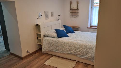 a bedroom with a bed with blue pillows on it at Chez Mémère Paulette in Châtres-sur-Cher