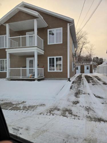 a house with snow on the driveway in front of it at Appartement de 2 chambre à la baie in Saguenay