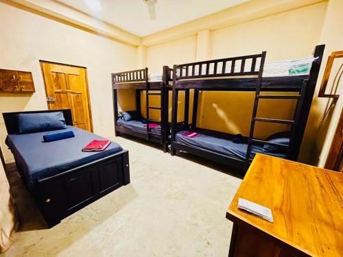 a room with two bunk beds and a table at OM Inn in Trincomalee