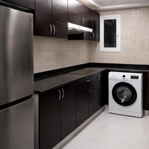 a kitchen with black cabinets and a washer and dryer at Burdubai Vacation Homes in Dubai