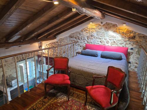 a bedroom with a bed and two red chairs at Loft Naevio in Ferentino