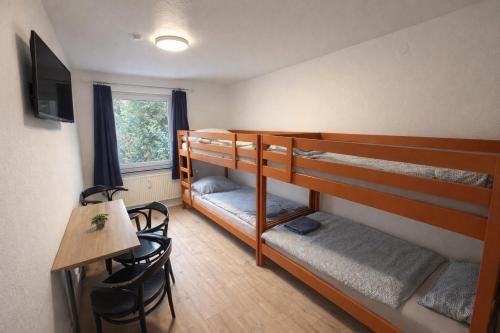 a room with three bunk beds and a table and a desk at Quartier An der Rennbahn in Bremen
