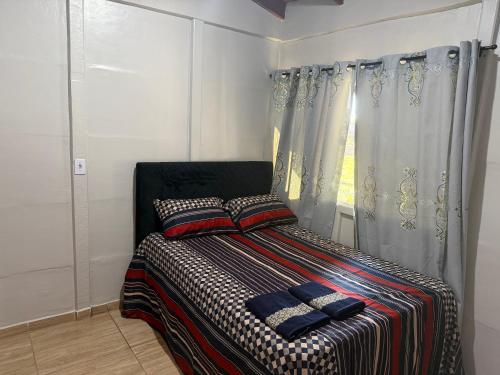 a small bedroom with a bed with a window at Chácara pontarolo in Guarapuava