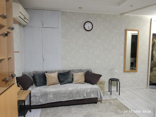 a living room with a couch and a clock on a wall at Бухар жырау 45 in Karagandy