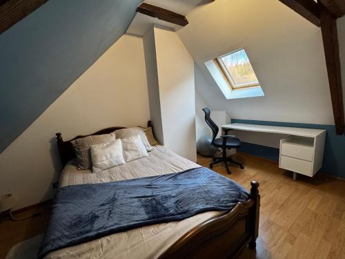 a bedroom with a bed and a desk in a attic at L écrin de l aube in Grainville-la-Teinturière