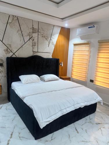 a bedroom with a large bed with a black headboard at De Rex Luxury Apartment in Akwa