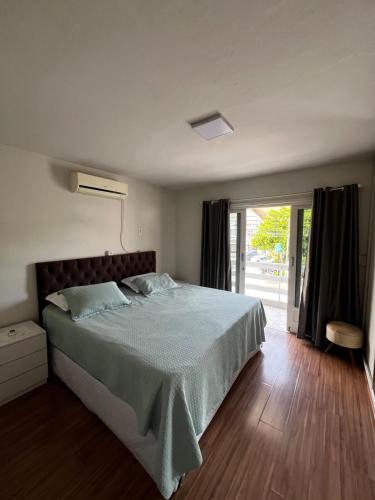 a bedroom with a bed and a sliding glass door at Casa com churrasqueira e ar para até 8 pessoas in Guabiruba