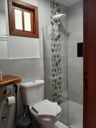 a bathroom with a toilet and a glass shower at Pousada Atlantik-Haus in Costa Dourada