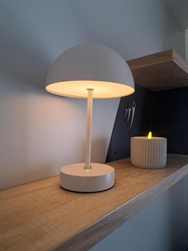 een lamp op een plank met een kaars erop bij Chez Achille in Marcilly-sur-Eure