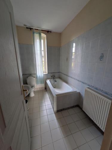 a white bathroom with a tub and a toilet at Gîte de Navarre in Billy