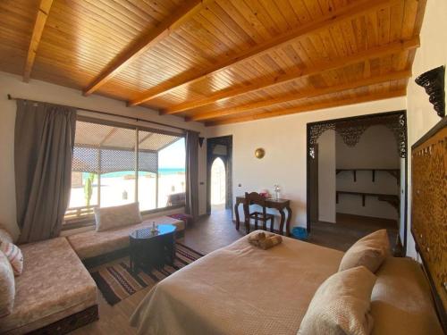 a bedroom with a large bed and a living room at maison d'hôtes la merveille in Dakhla