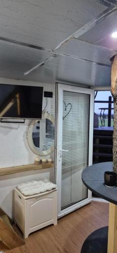 a living room with a table and a glass door at The Orchard's Nook Treehouse in Cottenham