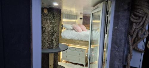 a small bedroom with a bed and a mirror at The Orchard's Nook Treehouse in Cottenham