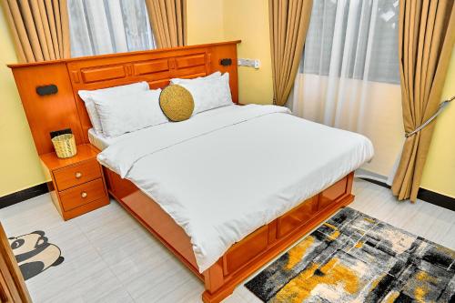 a bedroom with a large bed with a wooden headboard at Ngao Apartment and Suites Dodoma in Dodoma
