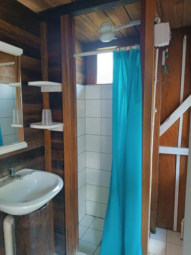 a bathroom with a sink and a blue shower curtain at Lodge France Amazonia in Puerto Misahuallí