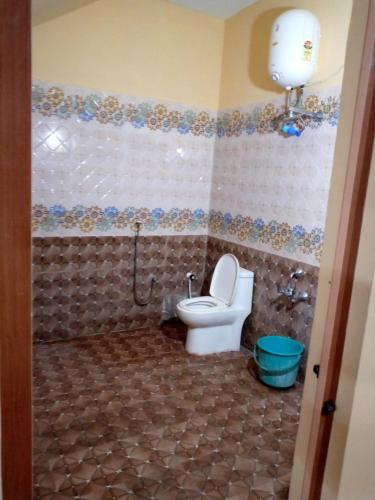 a bathroom with a toilet and a tiled floor at Vibheeshan Villa in Yelagiri