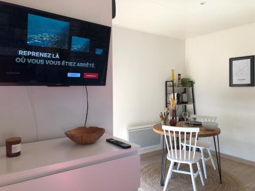 a living room with a table and a tv on a wall at Tiny House le Cocon de Jardin in Saverne