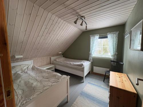 a bedroom with a bed and a desk and a window at Åker Lilläng Strandstugan in Åker