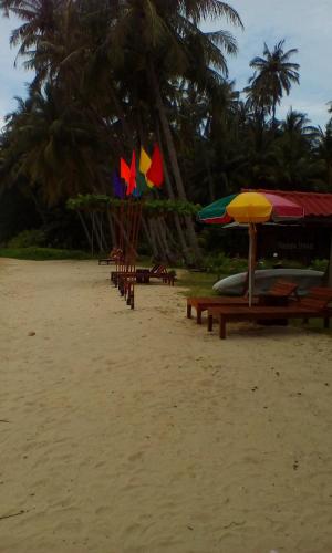 a beach with benches and umbrellas on the sand at Happy Days Resort in Ko Mak