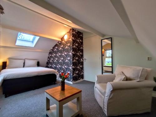 a bedroom with a bed and a couch and a table at Morning Glory, Huisje Dahlia in Beekbergen