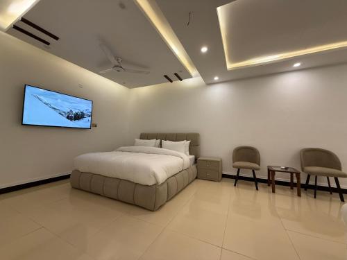 a bedroom with a bed and a tv on the wall at Sunrise Rest House in Islamabad