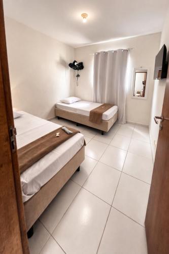 two beds in a room with white tile floors at Apartamento simples e Familiar conforto e sossego in João Pessoa