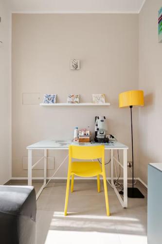 a white table with a yellow chair in a room at Studio Alpha - relax e jacuzzi in Syracuse