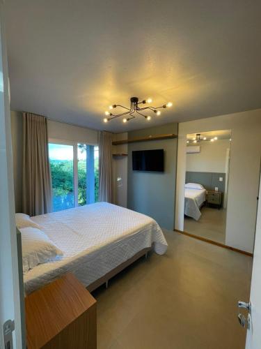 a bedroom with a large bed and a television at Refúgio das Araucárias in Nova Petrópolis