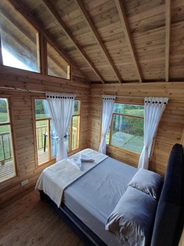 a bedroom with a bed in a wooden house at Cabañas Buenos aires in Guadalupe
