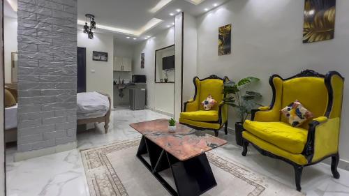 a living room with two yellow chairs and a table at Casa Pyramids View in Cairo