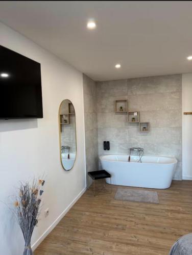 a bathroom with a white tub and a tv at Hammam du château in Francheville