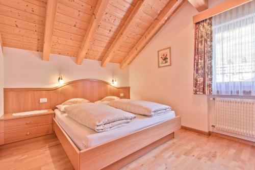 1 dormitorio con 1 cama en una habitación con ventana en Appartamenti Vilin, en San Cassiano
