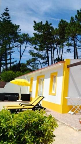 a yellow building with chairs and an umbrella at Casas de Campo - Real Mar in Ericeira