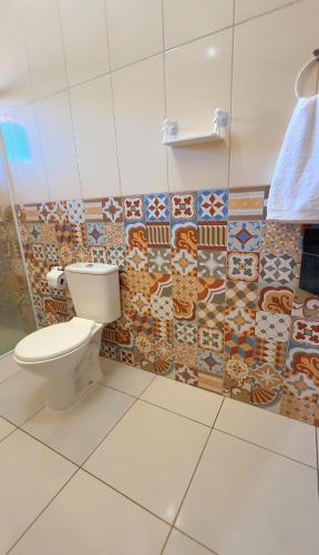 a bathroom with a toilet and tiles on the wall at Pousada Fielder e Anacleto in Penha