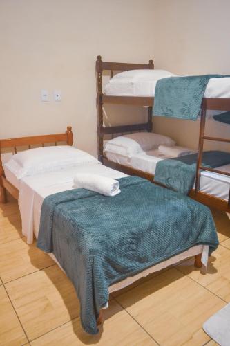 a room with two bunk beds with a green blanket at Pousada Fielder e Anacleto in Penha