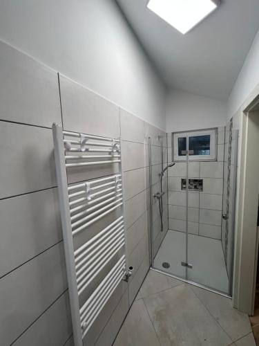 a white bathroom with a shower and a glass door at Königshof Studio in Monschau