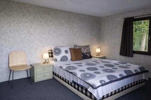 a bedroom with a bed and a chair and a window at Autocamp Kosmonosy in Mladá Boleslav