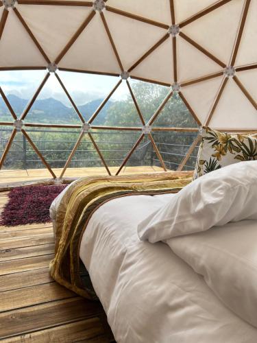 a bed in a room with a large glass window at La Meca Glamping in Guasca