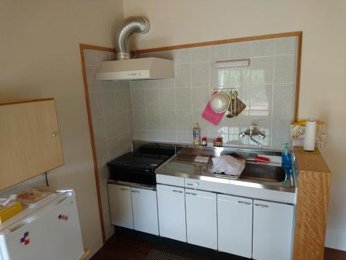 a kitchen with a sink and a stove at Kaeruya in Nakijin
