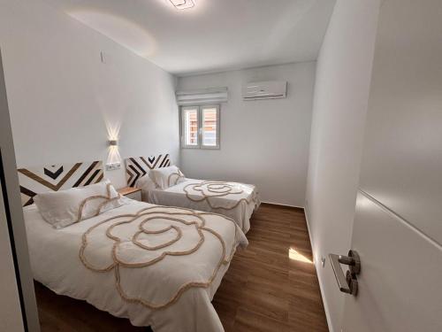 two beds in a room with white walls and wooden floors at Apartamento Maruchi in Santa Cruz de Mudela