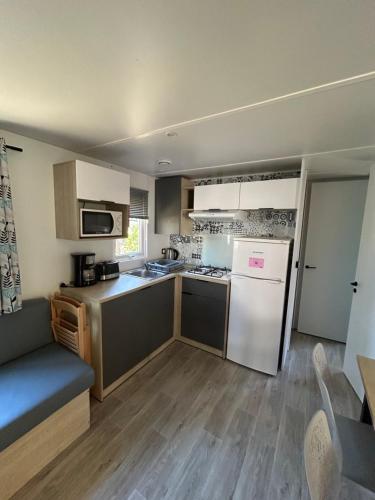 a kitchen with a white refrigerator and a stove top oven at Camping les Olyats in Seignosse