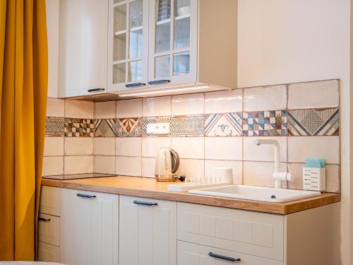 a kitchen with white cabinets and a sink at Apartmán Mick Jagger in Nymburk