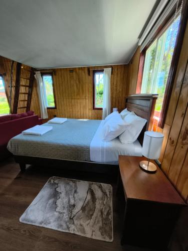 a bedroom with a bed and a table and windows at Cabañas CyG - Chaitén in Chaitén