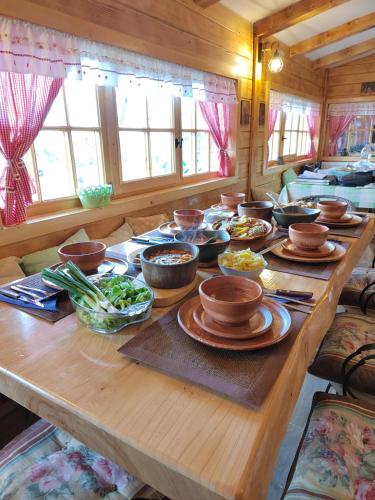 a long wooden table with bowls and plates of food at Domacinstvo Majovac in Drenova