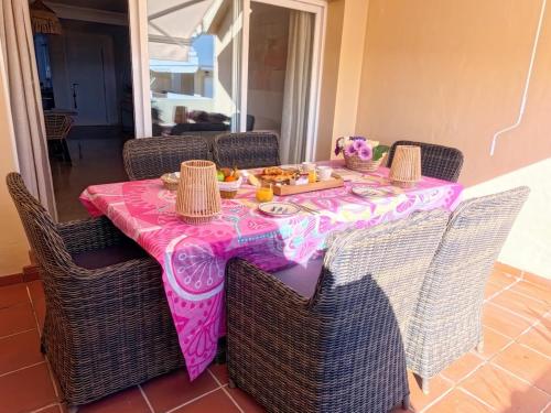 a pink table with wicker chairs with food on it at NEW Duplex Penthouse, Spectacular Ocean View in Manilva
