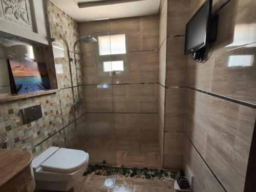 a bathroom with a toilet and a television on the wall at Royal villa in Ajman