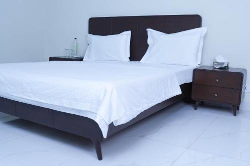 a large bed with white sheets and a night stand at Zubi Guest House in Dargai