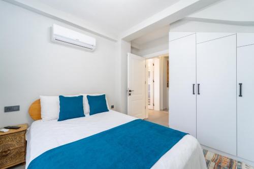 a white bedroom with a large bed with blue pillows at Villa Aden in Fethiye
