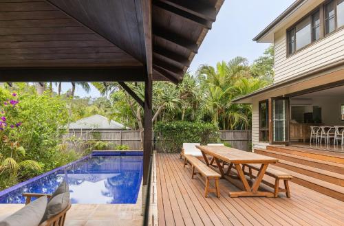 a wooden deck with a picnic table next to a swimming pool at Away Guesthouse- Away on Shirley Lane in Byron Bay