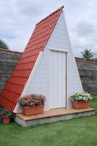a small house with a red roof and two plants at Acampamento Aloha solemar in Praia Grande